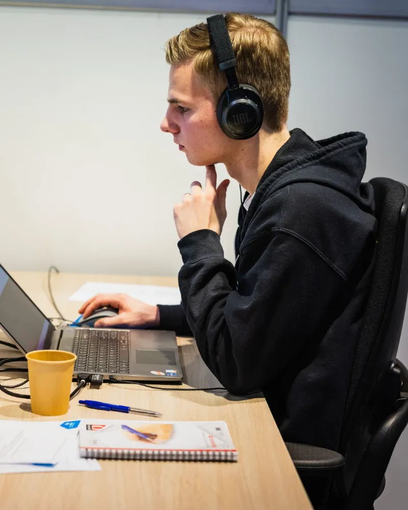 Tom Tiedemann aan het werk achter een laptop, met een koptelefoon op